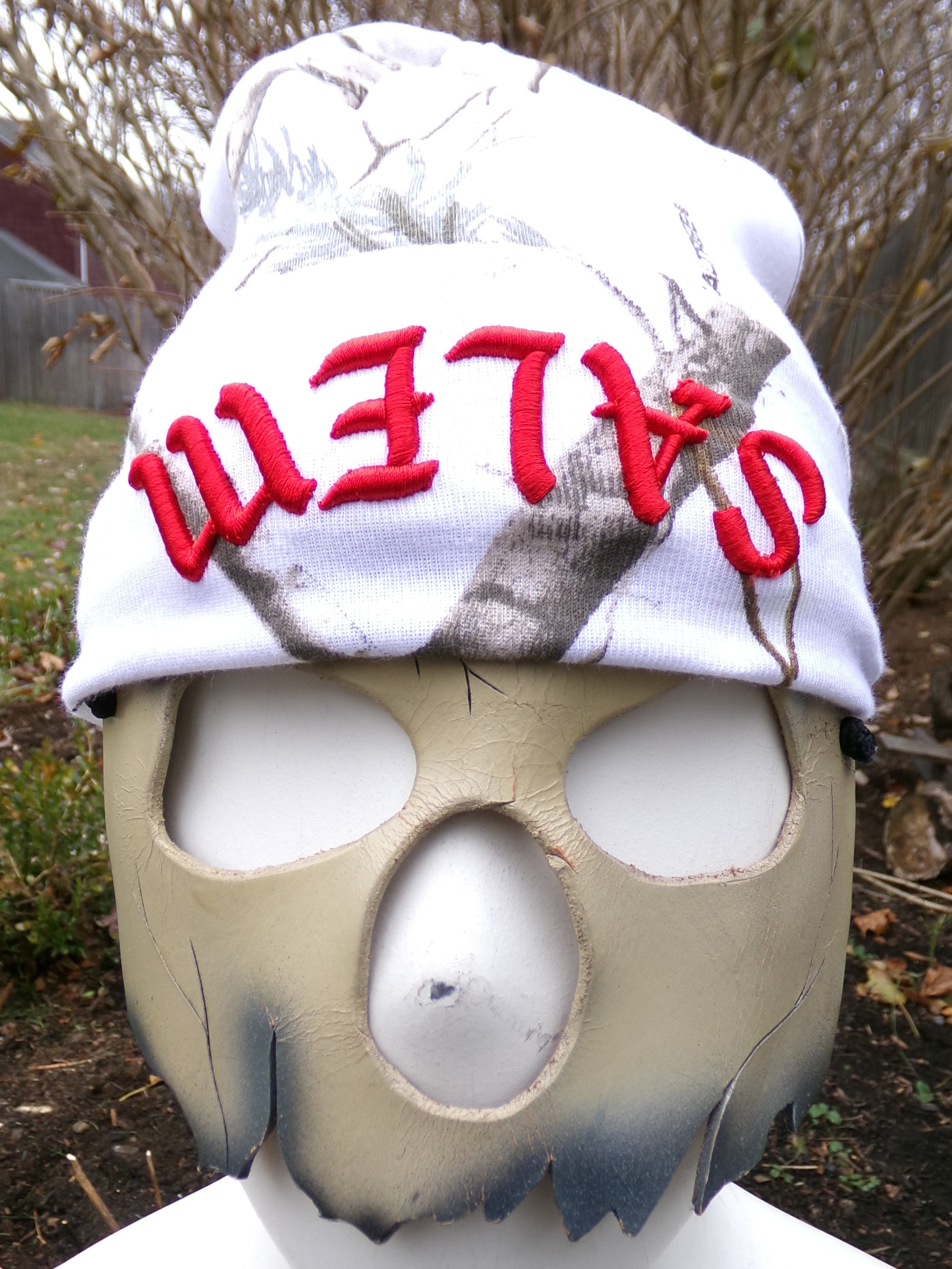 Person wearing a white cap with 'Salem' printed in red, outdoors.