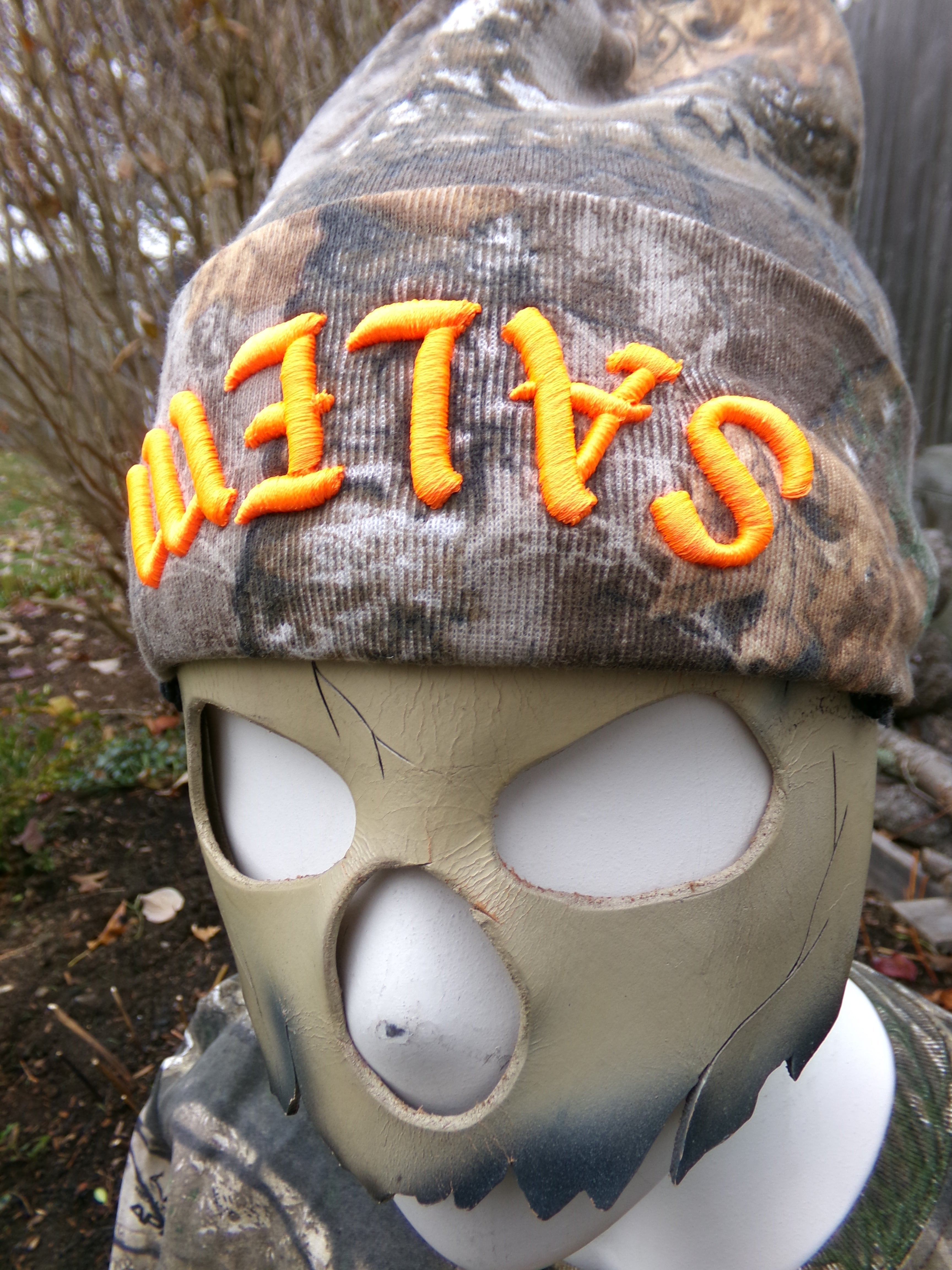 Camouflage clothing with 'SALEM' text and a tactical mask on a natural background