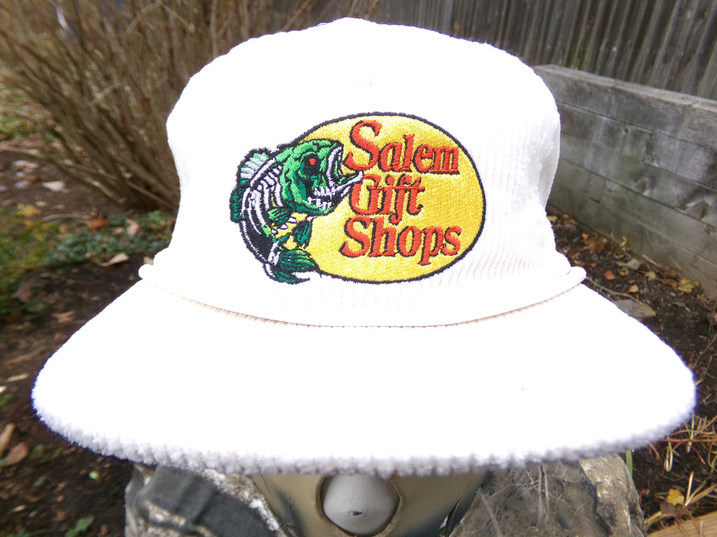 White bucket hat with 'Salem Gift Shops' logo on a blurred outdoor background